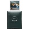 Green Instax instant camera with a white photo partially ejected showing three people on a couch. The image highlights the camera and the emerging photo content.