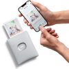 Hands use a smartphone to print a photo from the screen onto a portable Instax printer.