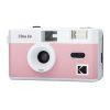 Pink and white retro-style compact camera with a prominent center lens and flash on top.