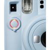 Close-up of a light-blue instant camera showing the shutter button with a red ring, the built-in flash above it, and part of the lens.