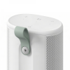 White cylindrical portable speaker with a light-green hinged handle on the side and top control buttons (volume, power).