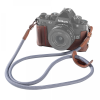 Nikon Zf mirrorless camera in a brown leather half-case with a gray woven strap attached.ไว้ Alternate: close-up of a Nikon camera with a leather wrap and long gray strap.
