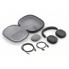 Wireless over-ear headphones with a carrying case, charging cables, and a compact charging puck laid out for travel.