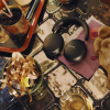 Black Sonos over-ear headphones resting on a colorful craft table with ribbons, paper, and a potted plant nearby.