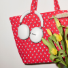 White Sonos over-ear headphones resting on a red quilted tote bag with yellow tulips nearby.